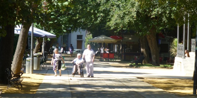 Imagen de archivo de una trabajadora de ayuda a domicilio paseando a un anciano por el parque 'Ramón Santaella'. Foto: TV Baena.