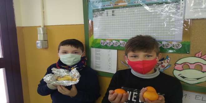 Dos alumnos del colegio Juan Alfonso de Baena con sus piezas de fruta junto al panel del 'Frutómetro'. Foto: CEIP Juan Alfonso de Baena.